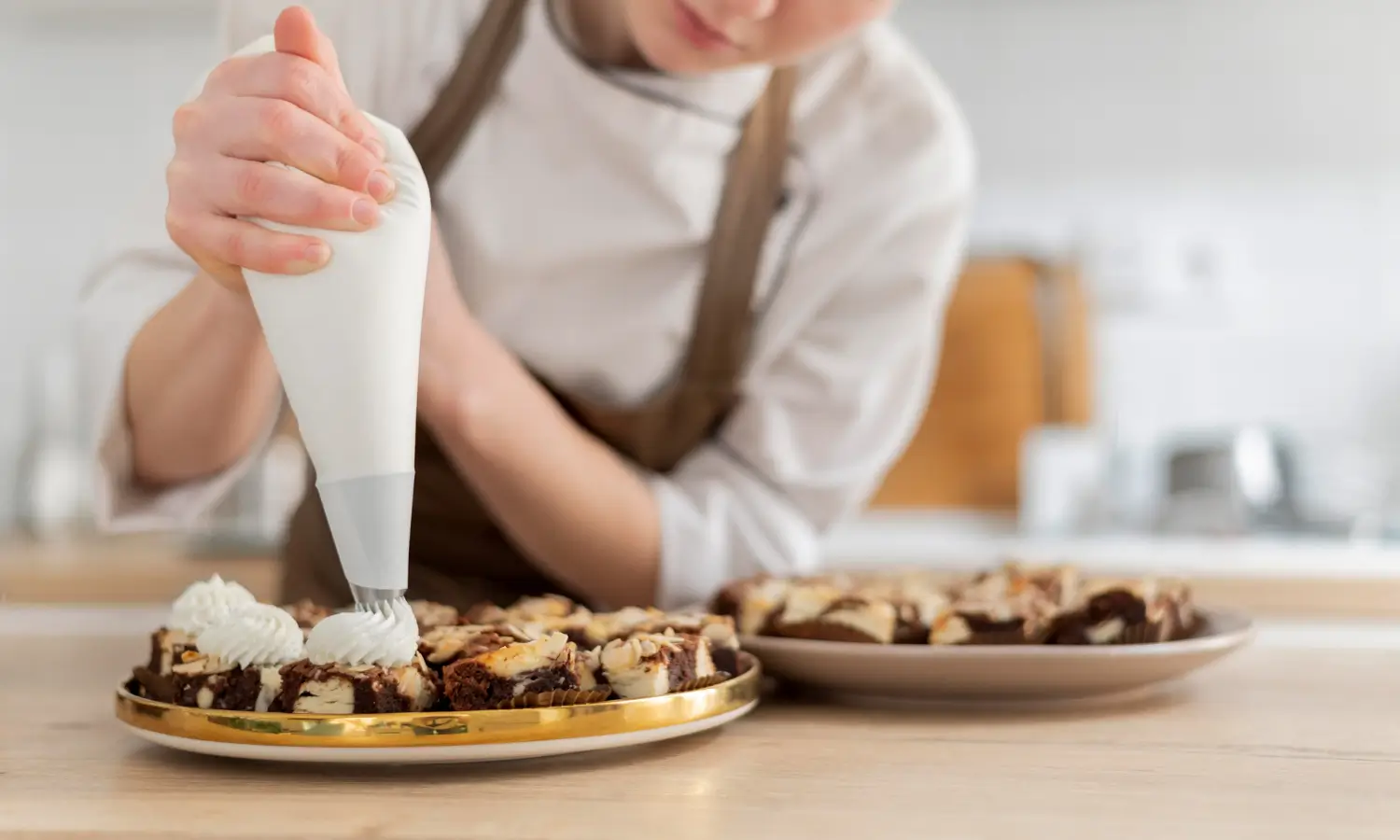 Chef decorando brownies con crema batida en una cocina moderna.